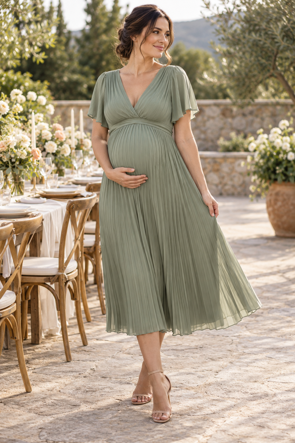 Pregnant adult model wearing a sage green pleated dress outdoors
